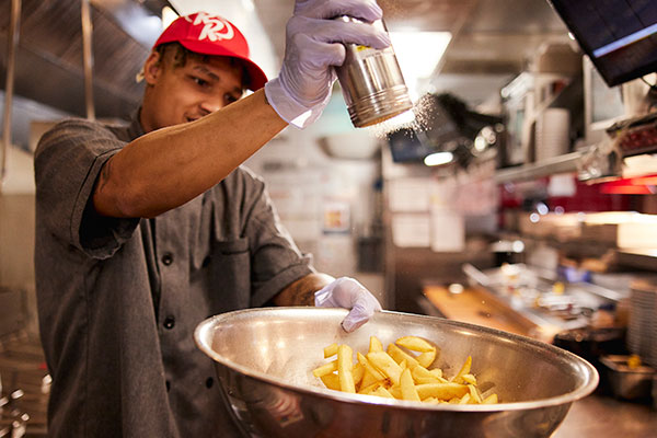 Team Member seasoning our famous steak fries